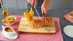 a person cutting up food on top of a wooden cutting board