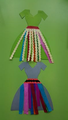 a paper dress made out of strips of colored paper on a green background with scissors