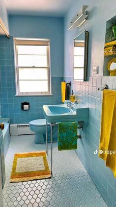 a blue bathroom with yellow towels hanging on the rack