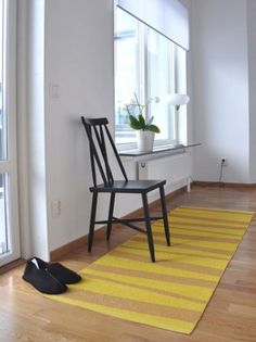 a chair sitting on top of a wooden floor next to a yellow and white rug