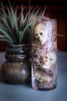 there are two vases with plants and skulls in them, one is filled with grass