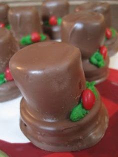 chocolate candies in the shape of top hats with holly decorations on red and white checkered tablecloth