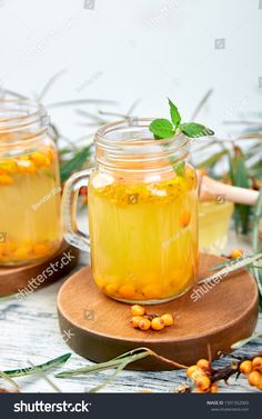 two mason jars filled with lemonade and garnished with mint leaves on a cutting board