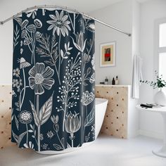 a bathroom with a blue shower curtain that has white flowers and leaves on it, next to a bathtub