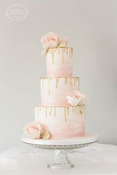 a three tiered cake with dripping icing and pink flowers on the top layer