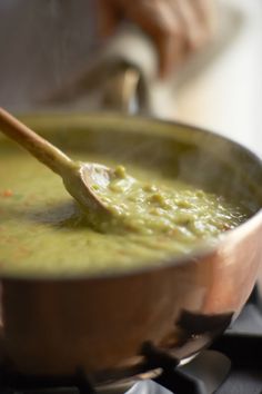 a wooden spoon in a pot filled with green soup