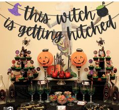 a table topped with lots of candy and halloween decorations on top of black cloth covered tables