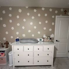 a baby's room with flowers painted on the wall and dressers in front of it