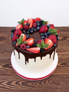 a chocolate cake topped with fresh fruit on top of a wooden table