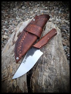 a knife and sheath sitting on top of a piece of wood