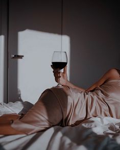 a woman laying in bed with a glass of wine