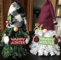 two gnomes sitting on top of a table next to each other with happy winter signs