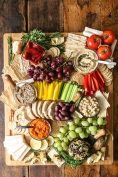 a wooden table topped with lots of different types of cheeses and vegetables on top of it