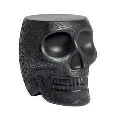 a black skull shaped vase sitting on top of a white surface with an intricate design