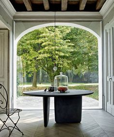 a table with a glass dome on it in front of an open door to a garden