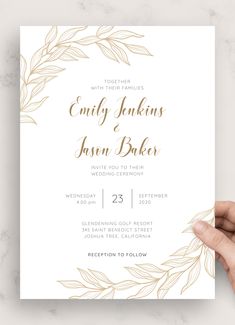 a hand holding up a wedding card with gold foil leaves on the front and bottom