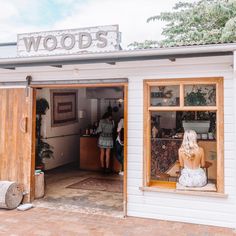 a woman sitting on a bench in front of a store with wooden doors and windows