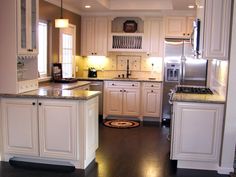 a large kitchen with white cabinets and wood floors