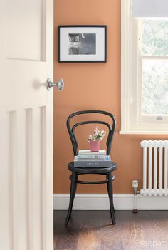 a chair with a book on it in front of a radiator and window