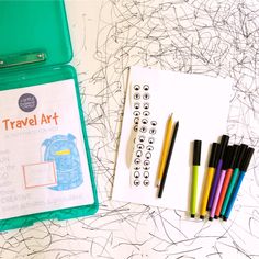 some pens and markers are sitting next to a clipboard with the words travel art written on it