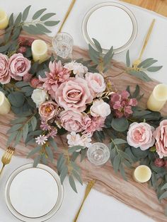 an arrangement of flowers and candles on a table with place settings for two people to sit at