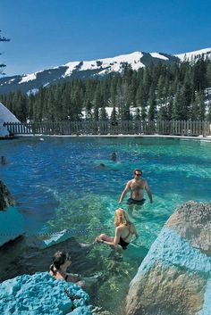 people are swimming in the water near some rocks