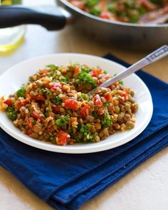 a white plate topped with lentils and broccoli on top of a blue napkin