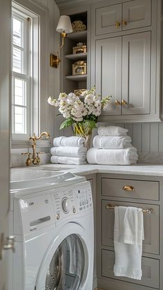 a white washer sitting next to a window in a room filled with lots of towels