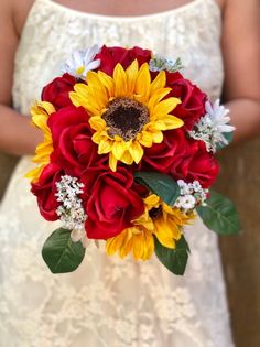 a bridal bouquet with sunflowers and red roses is held by a bride