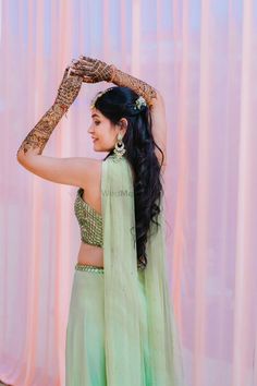 a woman in a green lehenga holding her arm up