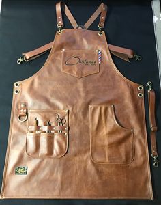 a brown leather apron with scissors on the front and two pockets in the back that are attached to each other