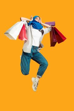 a person jumping in the air with shopping bags on their shoulders and hands behind them