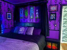 a bed with purple and black decor in a room that is lit up at night