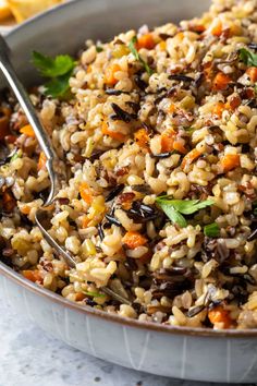 a bowl filled with rice, carrots and parsley on top of a table