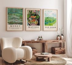 three paintings hang on the wall next to a chair and table in a living room