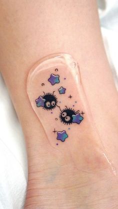 a small tattoo on the ankle of a woman's foot with stars and clouds