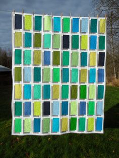 a quilt is hanging on a clothesline in front of a grassy area with trees