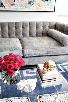 a living room with a couch, coffee table and flowers in vases on it