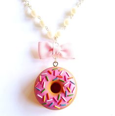 a donut with pink icing and sprinkles is hanging from a necklace