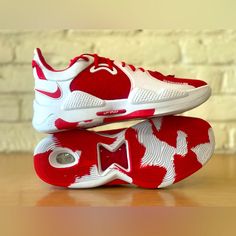 a pair of red and white shoes on top of a wooden table