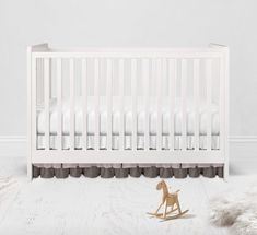 a white crib with a rocking horse next to it