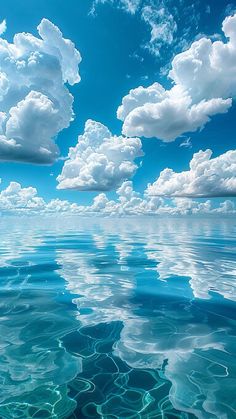 the water is very clear and blue with some clouds in the sky above it on a sunny day