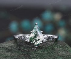 a green and white diamond ring sitting on top of a rock