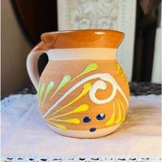 an orange and yellow vase sitting on top of a white doily covered table cloth