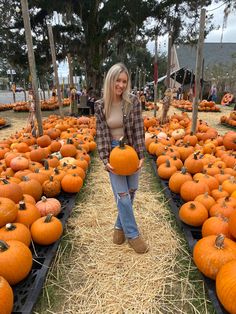 a woman standing in front of rows of pumpkins