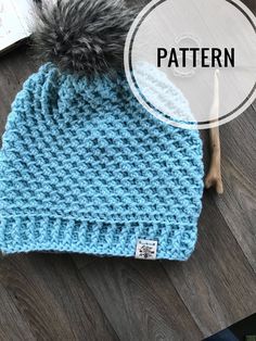 a blue crocheted hat with a pom - pom on top and the words pattern below it