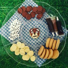 a clear plate topped with lots of cookies and pastries on top of a green grass covered field