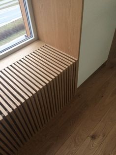 a wooden bench sitting next to a window on top of a hard wood flooring