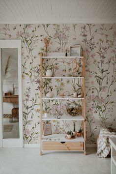 a room with floral wallpaper and wooden shelves