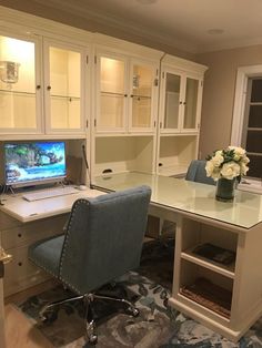 a desk with a computer on top of it in front of some cabinets and drawers